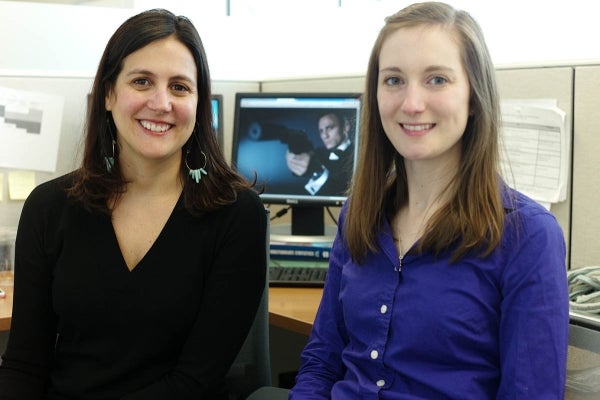 Amy Bleakley and Morgan Ellithorpe seated and smiling together for the picture. behind them is a computer screen with a show playing. They look like they are in an office.