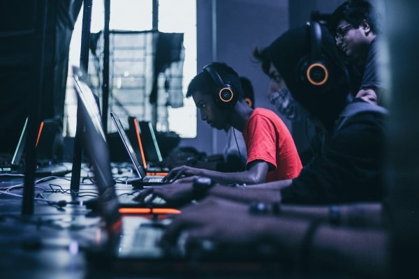 Teenagers wearing headphones and working on computers