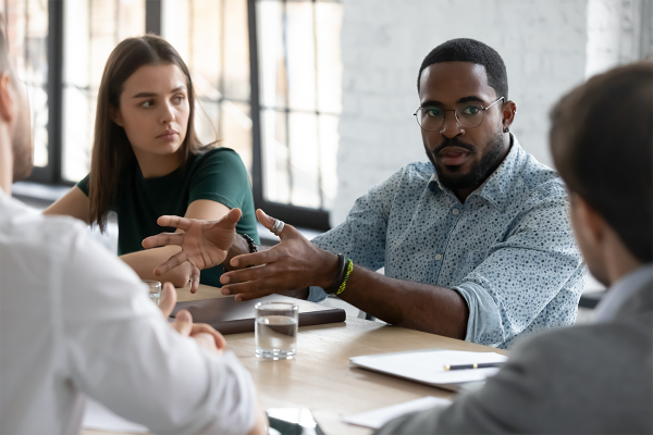 Man speaking persuasively to others at a work meeting