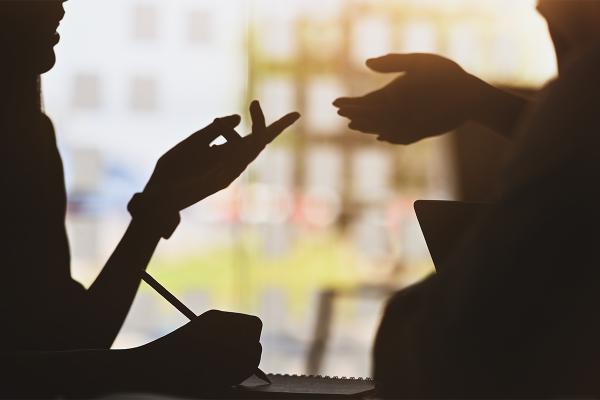 Silhouette of two people talking and using persuasive hand motions