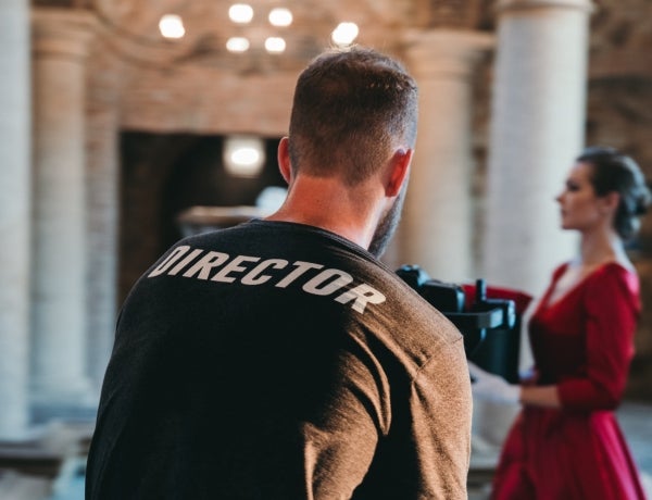 Film director filming a woman walking in a red dress