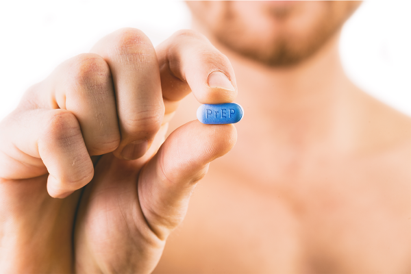 Man holding an HIV prevention pill towards the camera