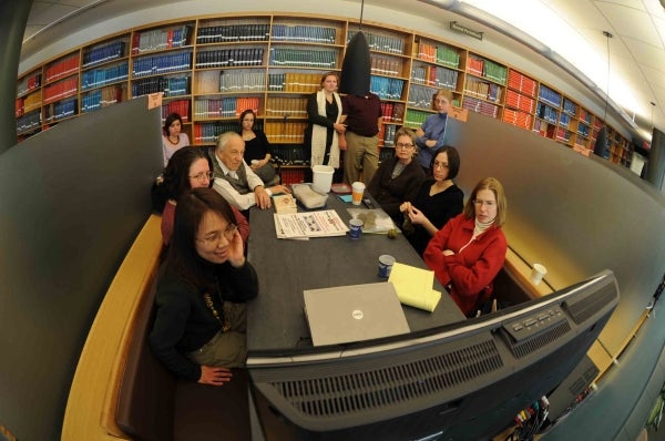 A group of people, including Elihu Katz and Min Zhong, huddled around a screen in a booth at the Annenberg School library. Photo is shot with a fish-eye lens.