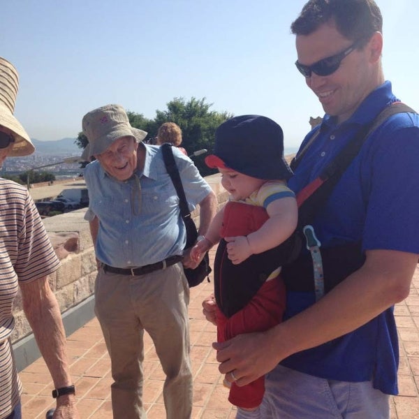 Elihu Katz smiling at a man wearing a baby in a baby carrier