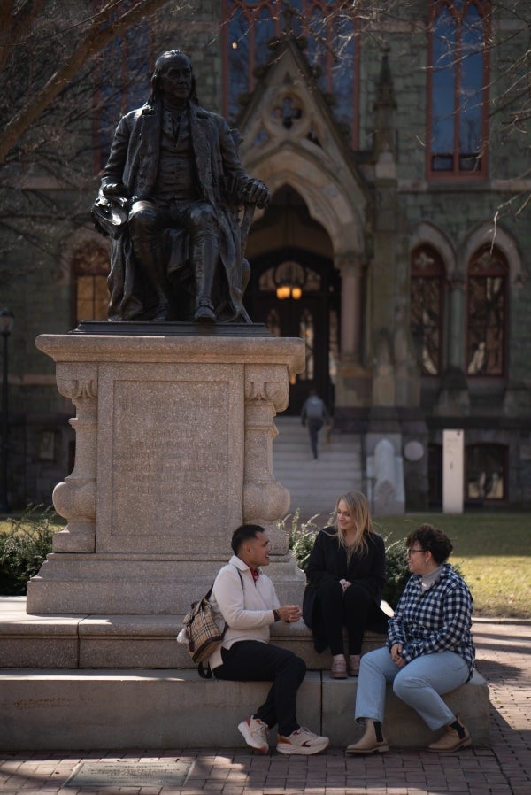 DMSI students Michael Ticzon, Amanda Labrador, and Jennifer Ingham in front of Benjamin Franklin statue on Penn's campus