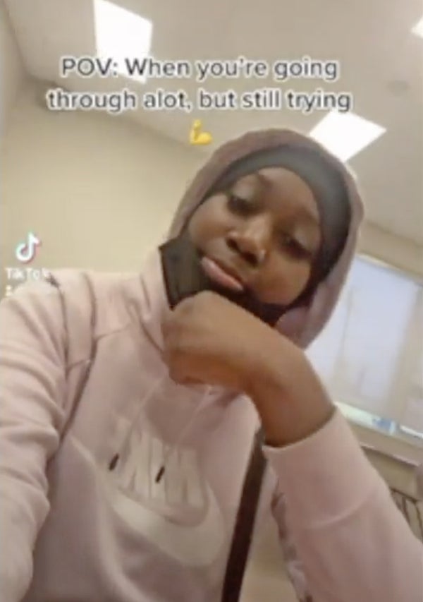 Screenshot of a TikTok with a woman smiling at camera and the words "When you’re going through a lot but still trying...”