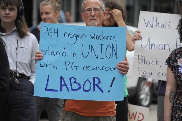 Protesters at a Pittsburgh Newspaper Guild rally. A man holds a sign that says, "PGH region workers stand in UNION with PG newsroom LABOR!"