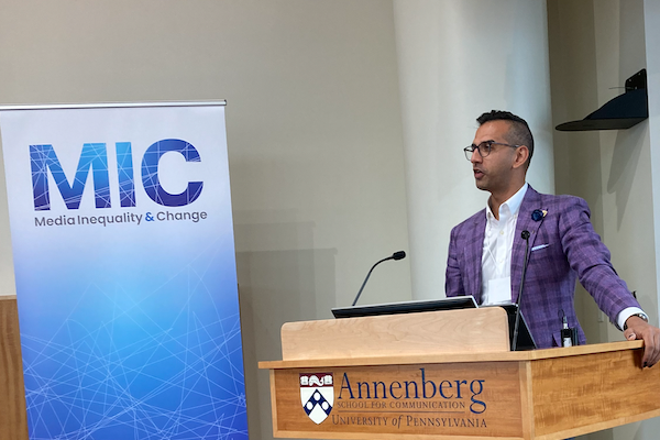 Christopher Ali (Ph.D. '13) speaks at a podium