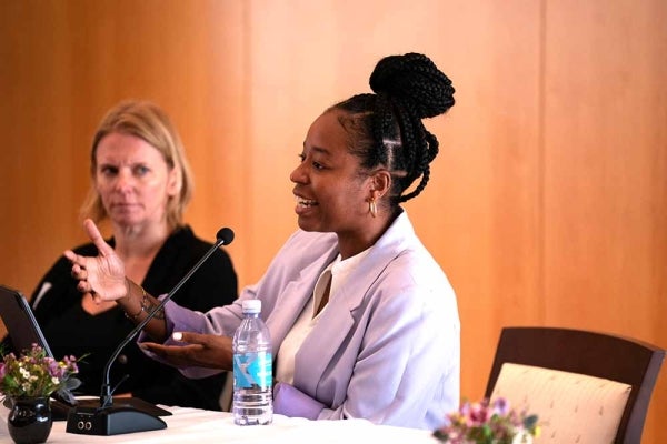 Philana Payton seated and speaking with a person also on the panel watching