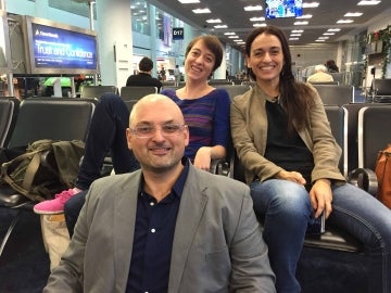 Three professors sitting at an airport gate, smiling