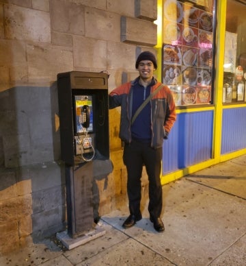 Man standing with a payphone on the street at night
