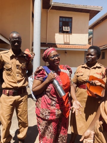 A Ugandan woman standing with two female prison guards
