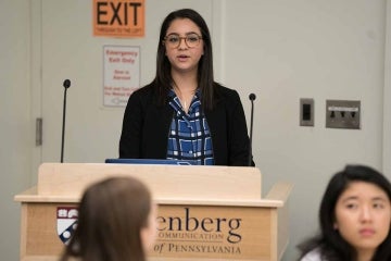 Student speaking at a podium with the Annenberg logo on it