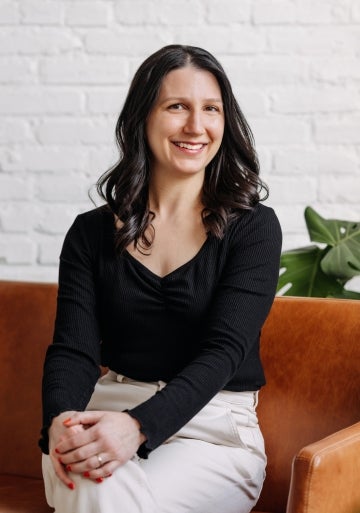 Emily Hund posing sitting down, crossing her legs and smiling