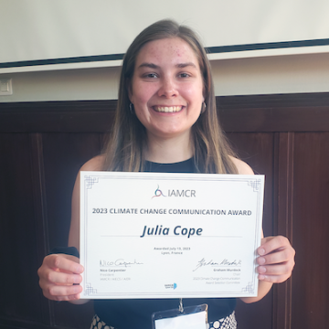 Julia Cope holds her Climate Change Communication Award certificate 