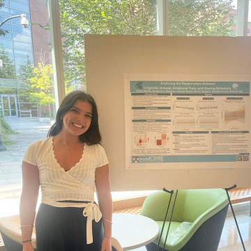 Arden Spehar stands in front of a poster presenting her research