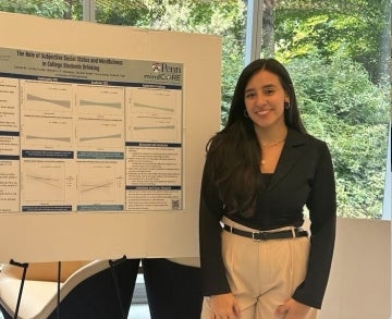 Denise Cortés-Cortés stands in front of a poster presenting her research